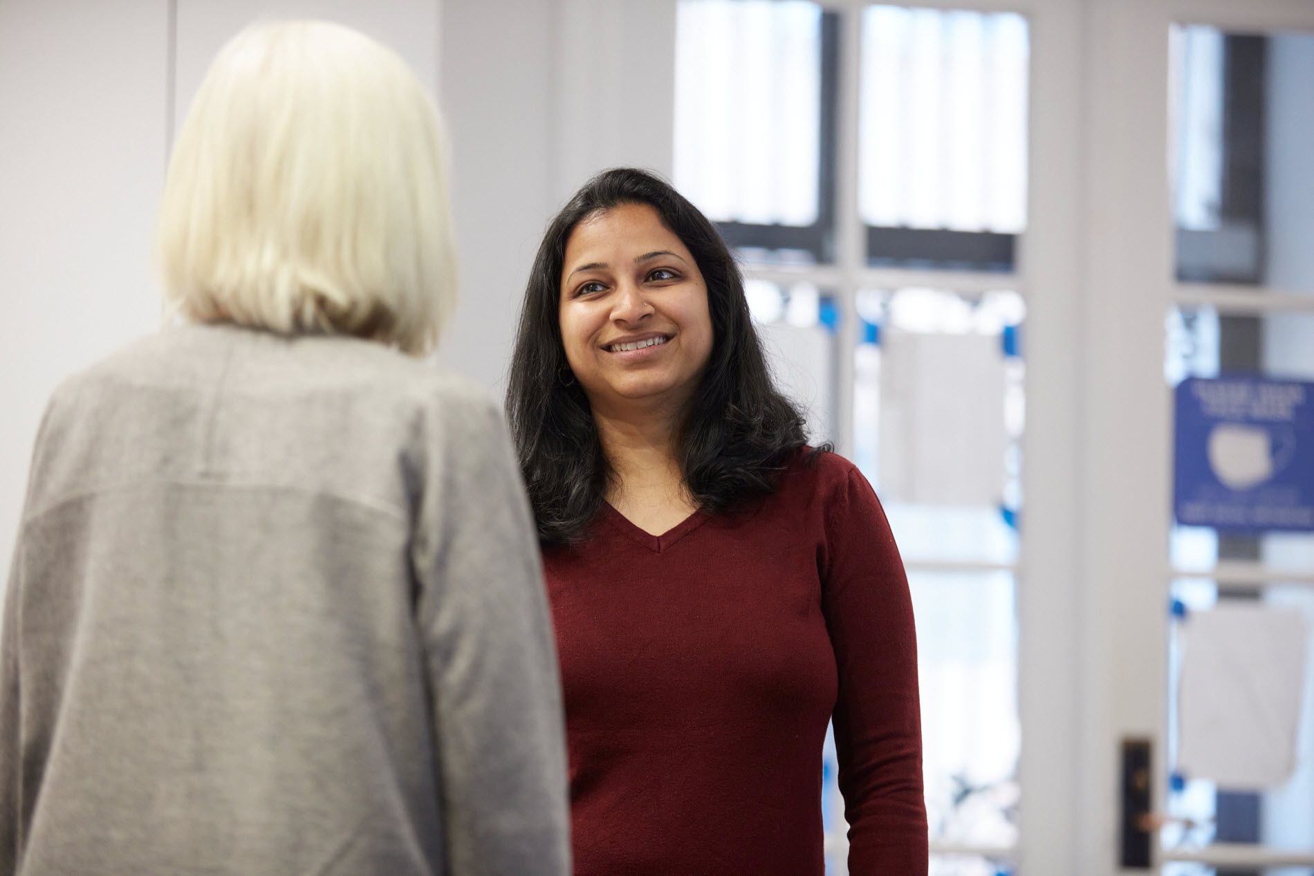 Woman smiling while speaking to another person.